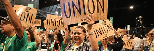 AFSCME members gathered in a crowd holding signs that look like cardboard with UNION in all caps on them